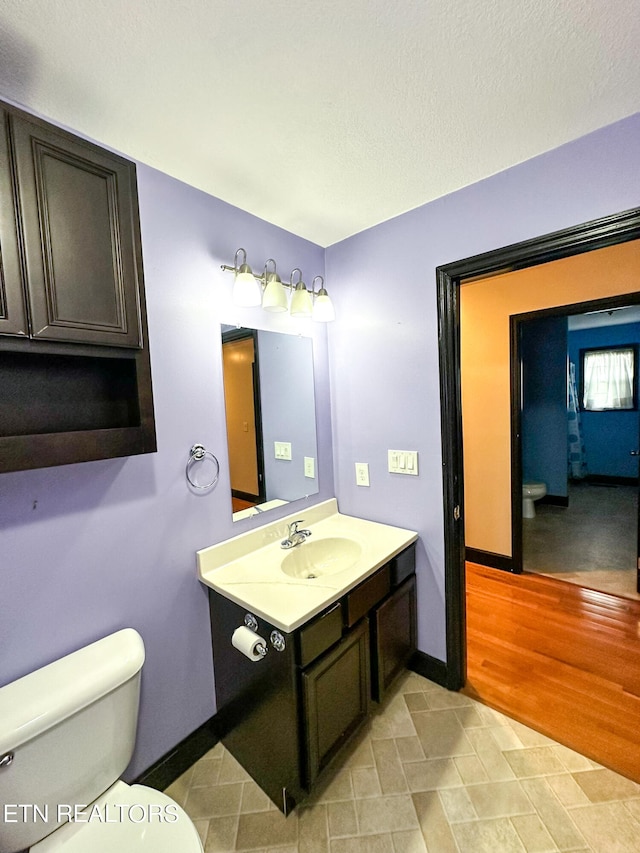 bathroom with wood-type flooring, toilet, and vanity