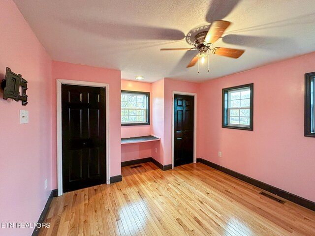 unfurnished bedroom with light hardwood / wood-style floors, multiple windows, and ceiling fan