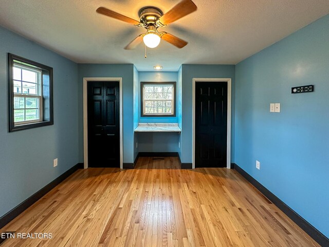 unfurnished bedroom with light hardwood / wood-style flooring, ensuite bath, and ceiling fan