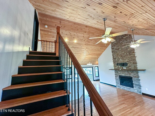 stairway featuring ceiling fan, a fireplace, hardwood / wood-style floors, and wooden ceiling