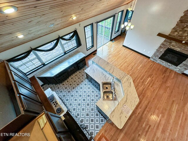 living room with high vaulted ceiling, hardwood / wood-style flooring, and a stone fireplace