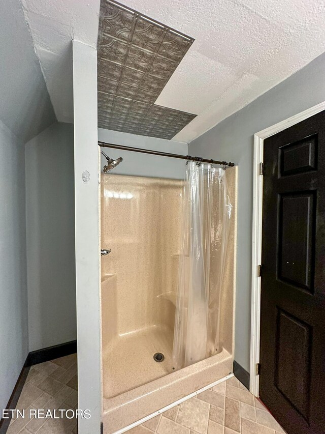 bathroom with a textured ceiling, a shower with curtain, and tile patterned flooring