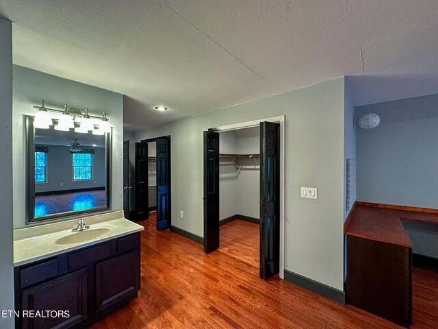 bathroom featuring ceiling fan, hardwood / wood-style floors, vanity, and a textured ceiling