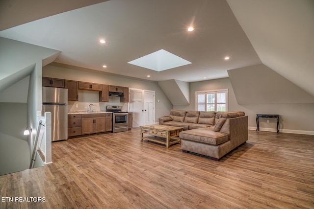 living room with baseboards, vaulted ceiling with skylight, light wood-style flooring, and recessed lighting