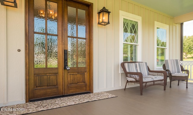 view of exterior entry featuring board and batten siding, french doors, and a porch