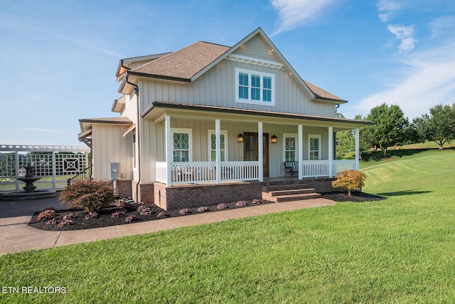 view of front facade featuring covered porch, a shingled roof, board and batten siding, and a front lawn