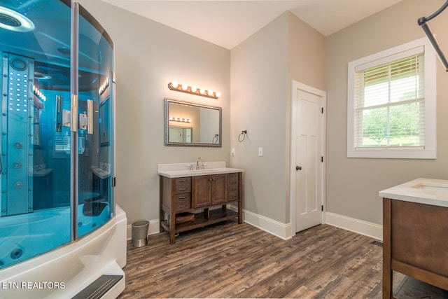 full bathroom featuring bath / shower combo with glass door, wood finished floors, vanity, and baseboards