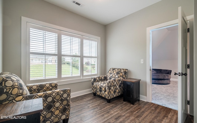 living area with dark wood-type flooring, visible vents, and baseboards