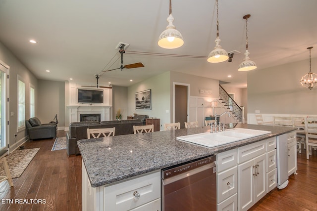 kitchen featuring a fireplace, a sink, white cabinetry, dishwasher, and a center island with sink