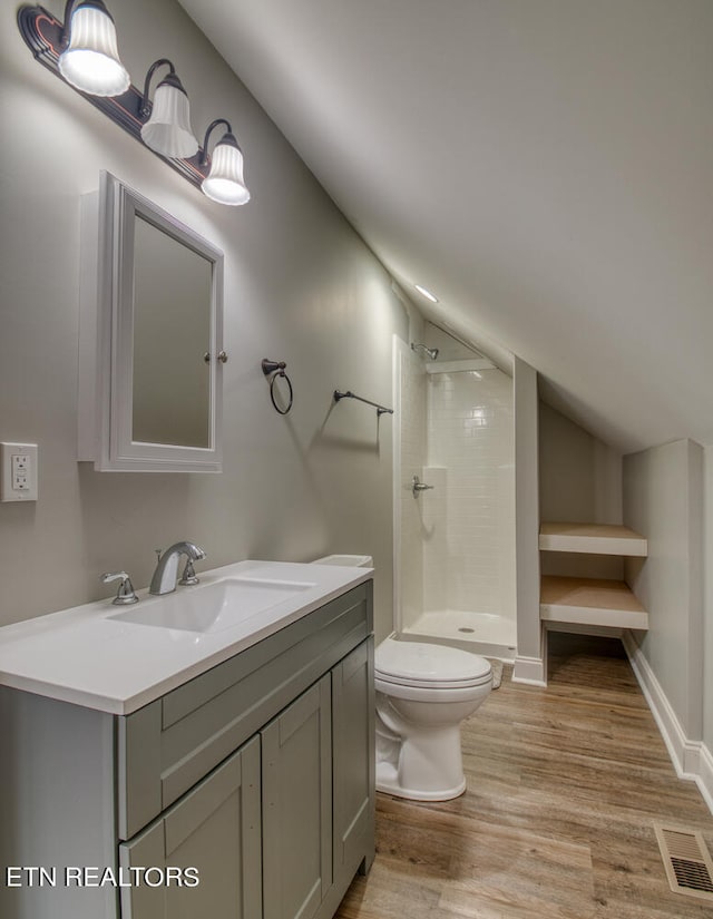 bathroom featuring visible vents, lofted ceiling, wood finished floors, vanity, and a shower stall