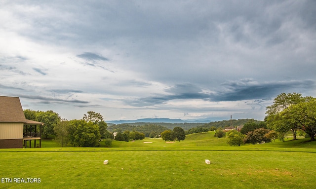 view of home's community featuring view of golf course, a lawn, and a mountain view