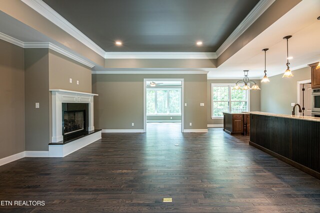 unfurnished living room with dark wood-type flooring, a notable chandelier, sink, and ornamental molding