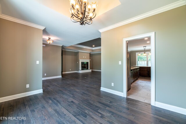 unfurnished room featuring a notable chandelier, ornamental molding, and hardwood / wood-style flooring