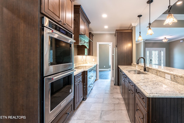 kitchen featuring pendant lighting, sink, light stone countertops, appliances with stainless steel finishes, and light tile patterned floors