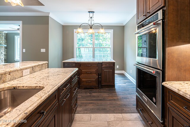 kitchen featuring dark hardwood / wood-style flooring, ceiling fan with notable chandelier, pendant lighting, stainless steel double oven, and dark brown cabinetry