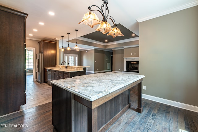 kitchen featuring dark brown cabinets, decorative light fixtures, light stone countertops, a center island, and dark wood-type flooring