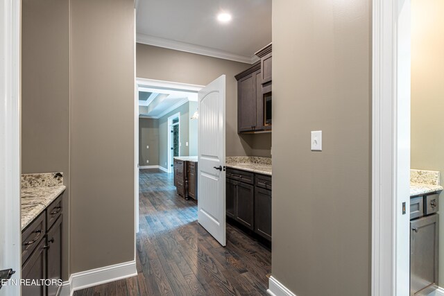 interior space featuring dark brown cabinetry, crown molding, dark hardwood / wood-style floors, and light stone counters