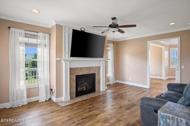 living room featuring a tile fireplace, ceiling fan, wood-type flooring, and ornamental molding