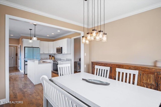 dining area with crown molding, dark hardwood / wood-style flooring, sink, and an inviting chandelier