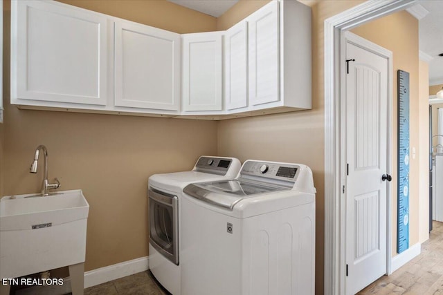 washroom with independent washer and dryer, light hardwood / wood-style floors, sink, and cabinets