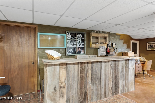 bar with tile patterned floors and a paneled ceiling