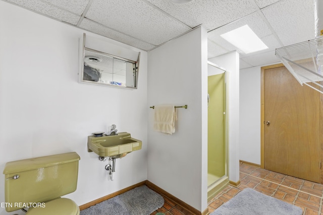 bathroom featuring a shower with door, tile patterned flooring, toilet, and a drop ceiling