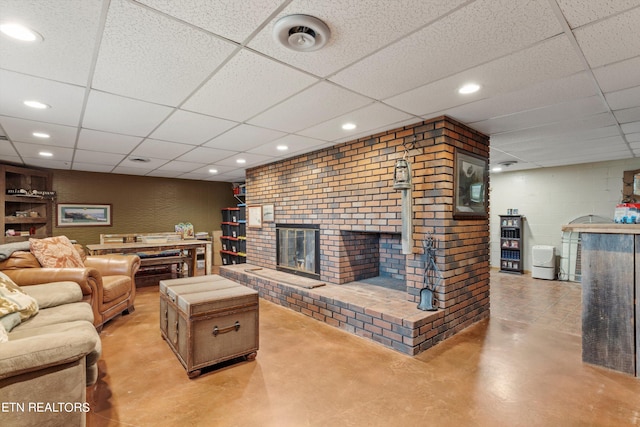 living room featuring built in shelves, a drop ceiling, concrete flooring, and brick wall