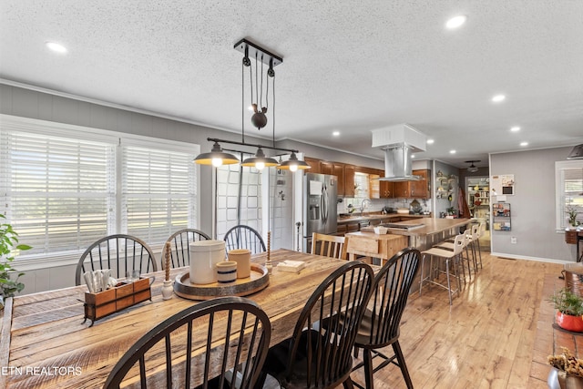 dining space featuring ornamental molding, light hardwood / wood-style floors, and a textured ceiling