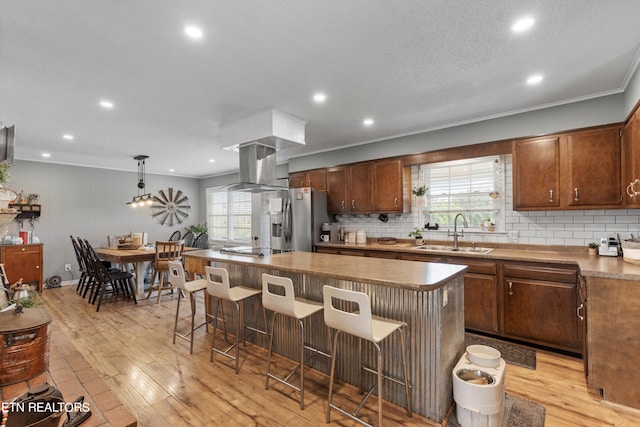 kitchen featuring a center island, light hardwood / wood-style floors, sink, island range hood, and stainless steel refrigerator with ice dispenser