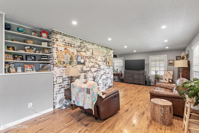 living room with light hardwood / wood-style floors, built in features, and a textured ceiling