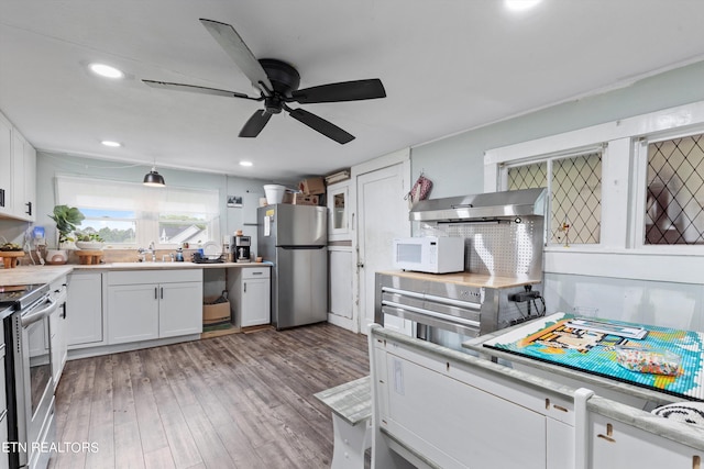 kitchen with tasteful backsplash, stainless steel appliances, white cabinets, light hardwood / wood-style floors, and ceiling fan