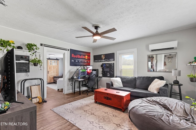 living room featuring a wall mounted AC, a textured ceiling, ceiling fan, and hardwood / wood-style floors