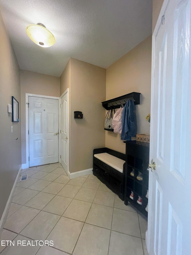 mudroom with a textured ceiling and light tile patterned flooring