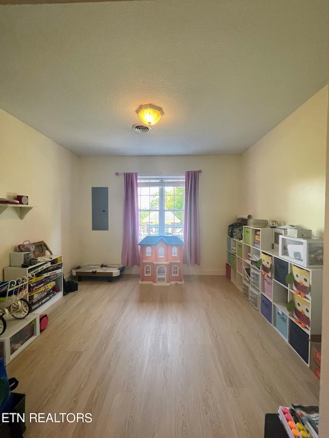 playroom featuring hardwood / wood-style floors, electric panel, and a textured ceiling