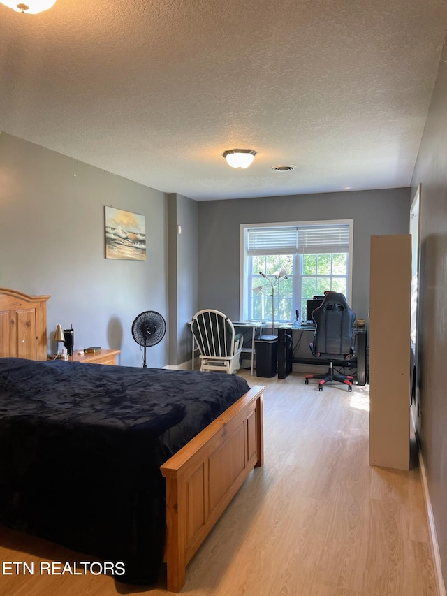 bedroom with a textured ceiling and hardwood / wood-style floors