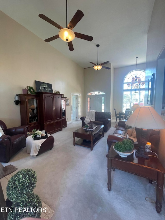 carpeted living room with ceiling fan with notable chandelier