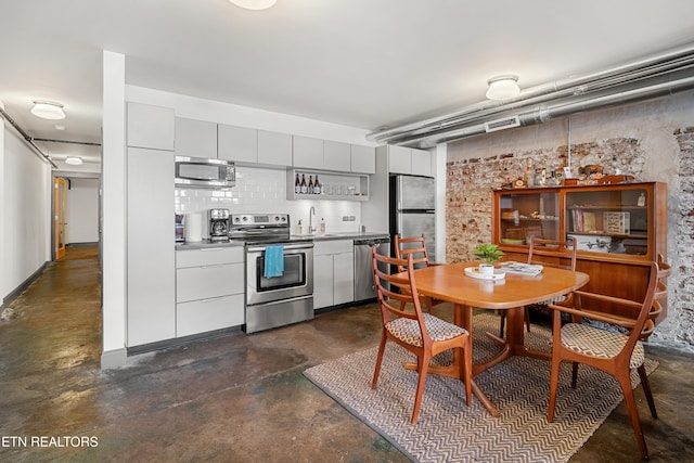 kitchen with appliances with stainless steel finishes, tasteful backsplash, sink, and gray cabinetry