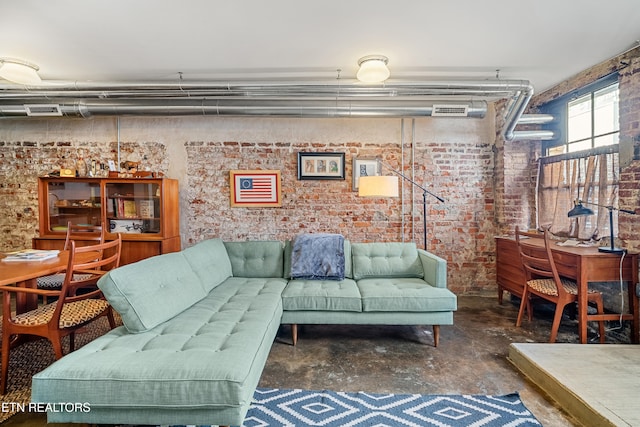 living room featuring concrete floors and brick wall