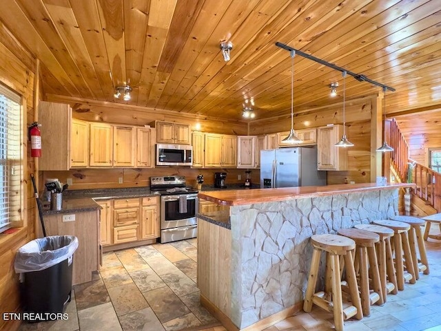 kitchen with appliances with stainless steel finishes, decorative light fixtures, a kitchen breakfast bar, light brown cabinets, and wooden ceiling