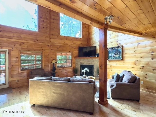 living room featuring a towering ceiling, wooden walls, light hardwood / wood-style floors, and wooden ceiling