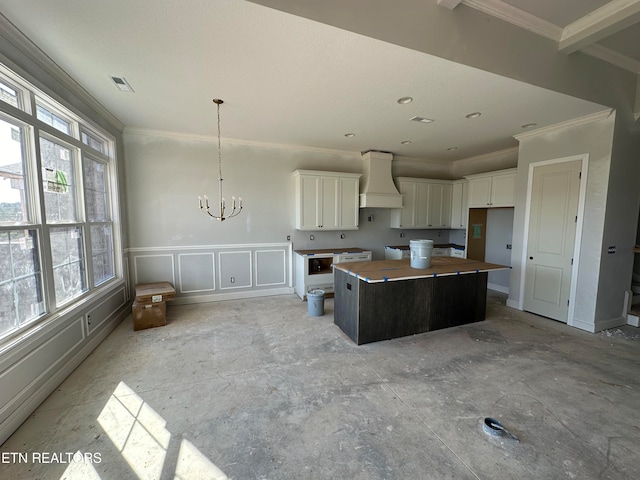 kitchen with a kitchen island, white cabinetry, custom exhaust hood, and plenty of natural light