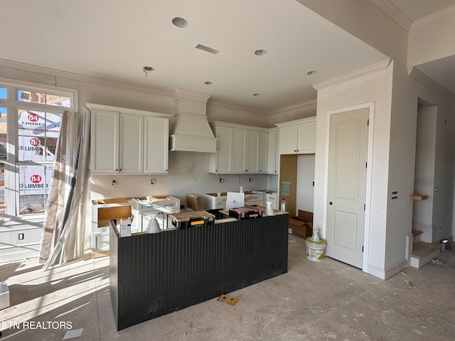 kitchen featuring ornamental molding, premium range hood, white cabinets, and a kitchen island