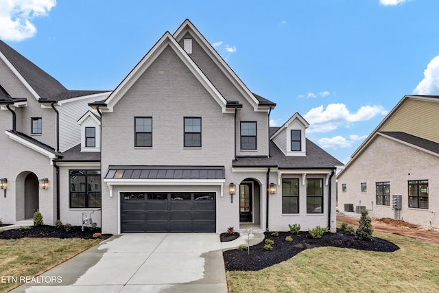 view of front of home featuring brick siding, an attached garage, driveway, and a standing seam roof