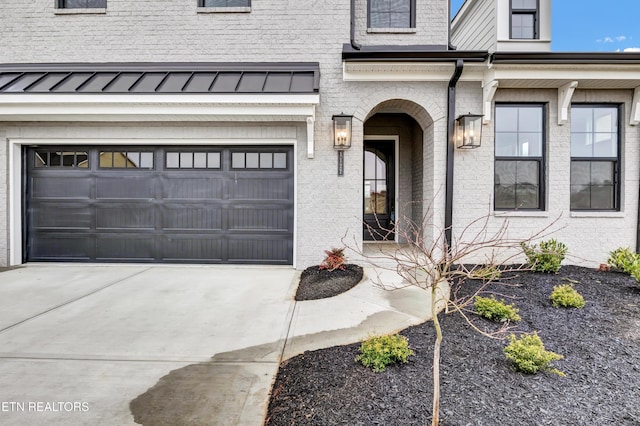 doorway to property with brick siding, a garage, and driveway