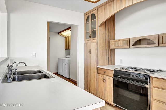 kitchen with a sink, light countertops, glass insert cabinets, washer and dryer, and black electric range oven