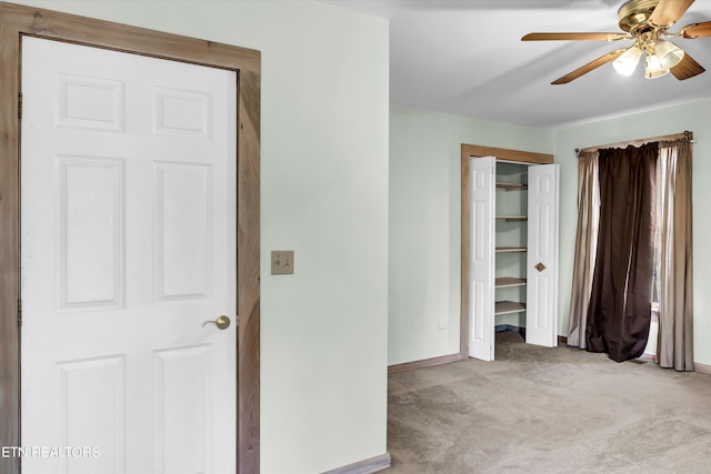 unfurnished bedroom featuring a ceiling fan, light colored carpet, baseboards, and a closet