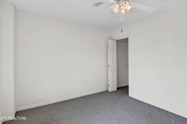 carpeted spare room featuring a ceiling fan and baseboards