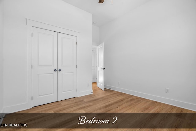 unfurnished bedroom with ceiling fan, a closet, and wood-type flooring