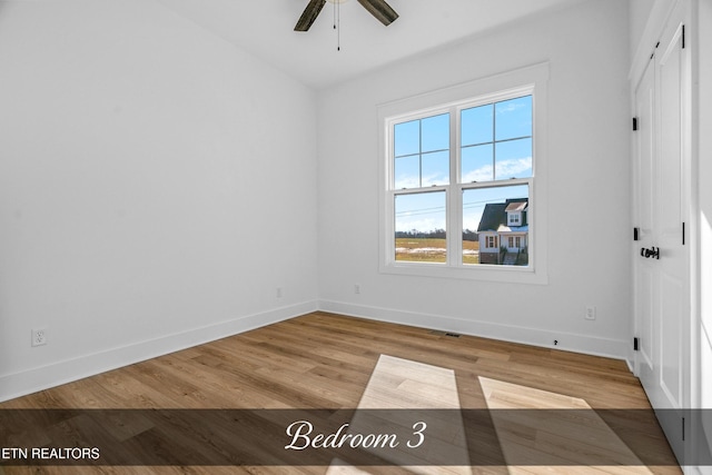 empty room with ceiling fan and light hardwood / wood-style flooring