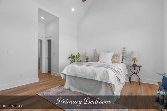 bedroom featuring high vaulted ceiling and light hardwood / wood-style flooring